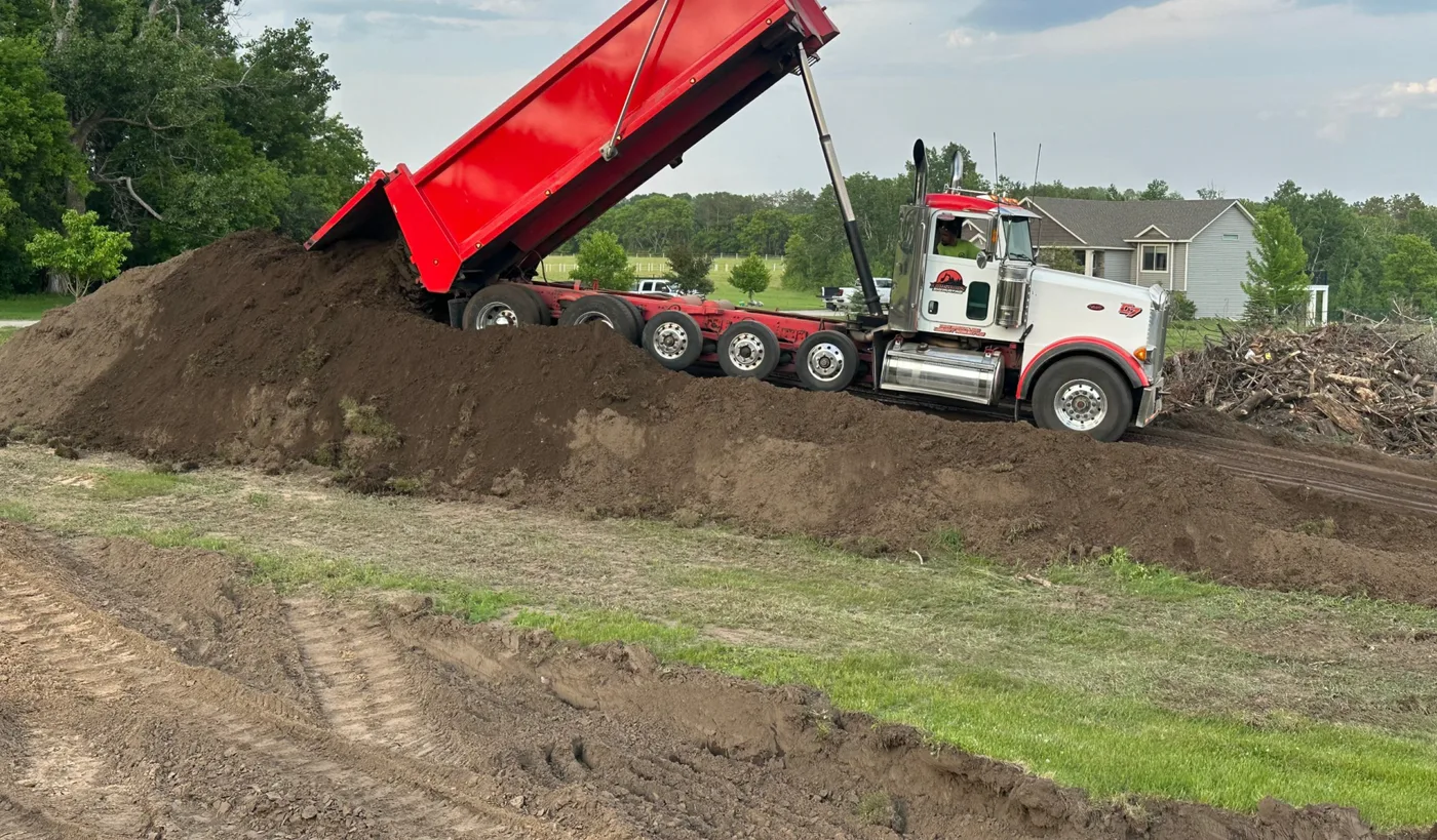 Tandem dump truck spreading a load of fill dirt