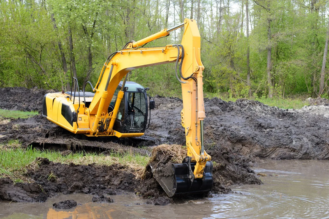 Excavator digging a ranch pond in wet clay southwest of Houston