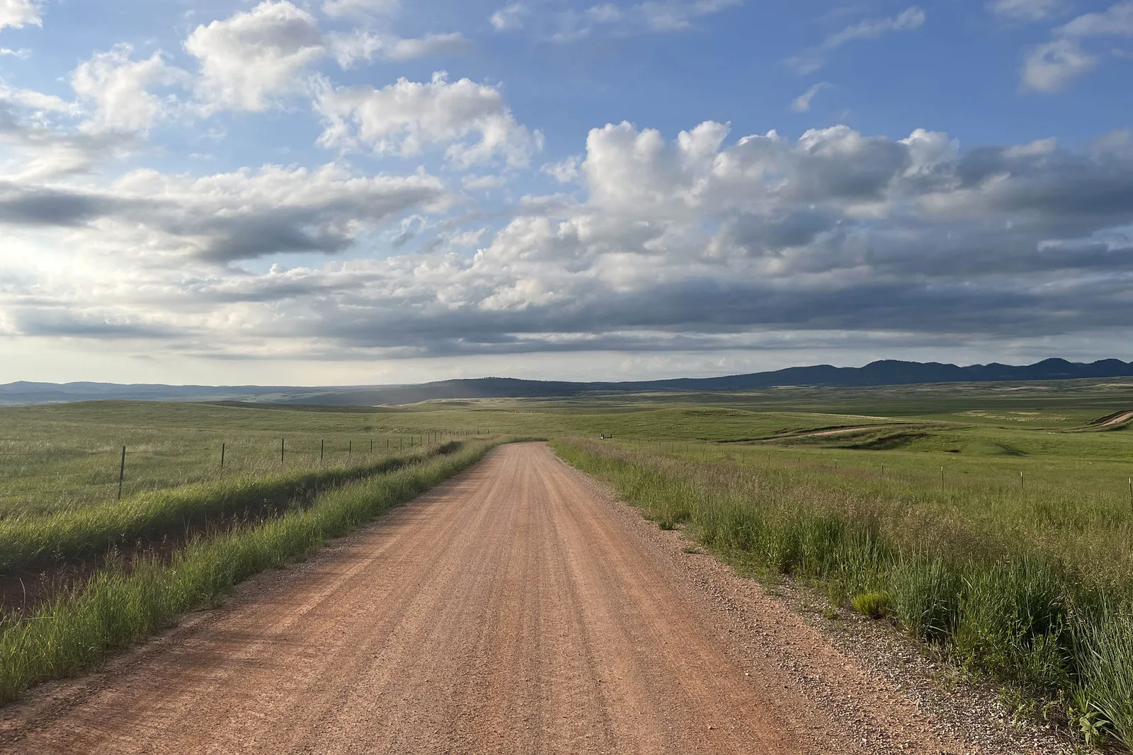 Crowned gravel drive running along a fence line across open prairie