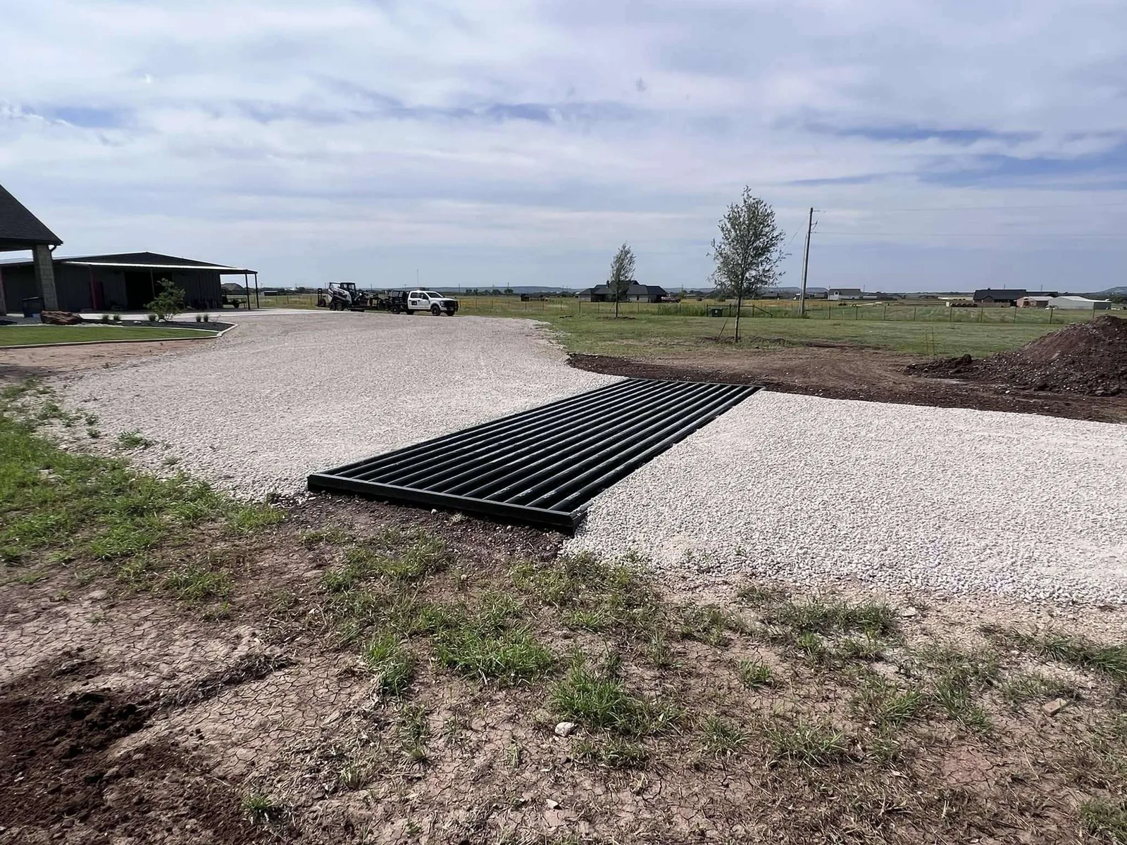 Gravel ranch driveway entrance with a cattle guard on Texas acreage